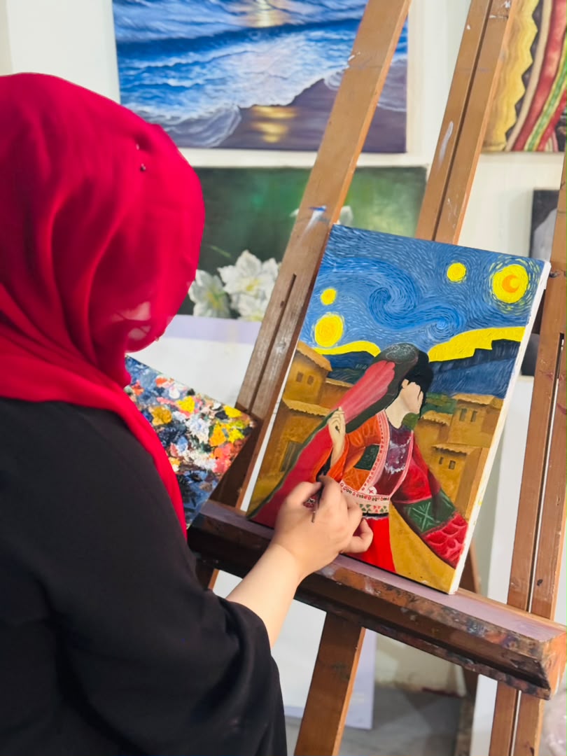 Zuhra painting a colorful Afghan-inspired artwork at her easel